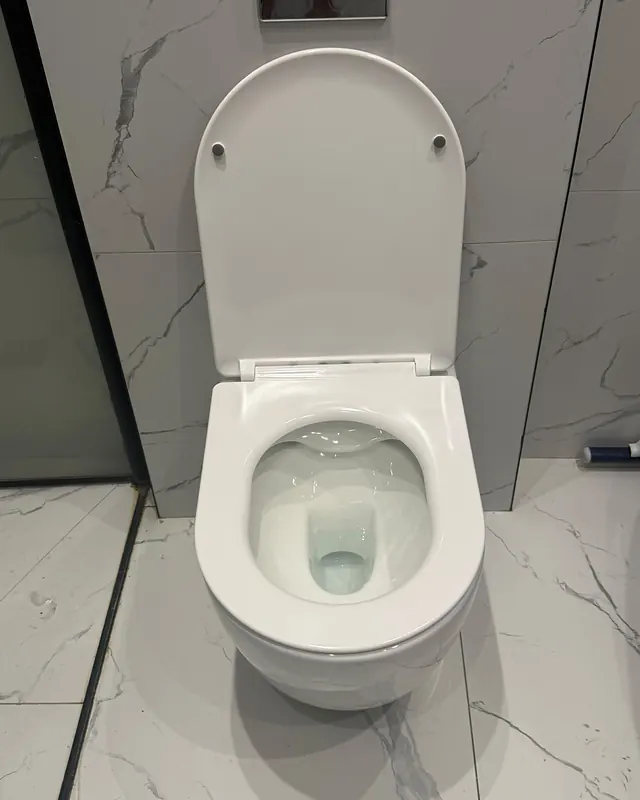 אסלה תלויה לבנה מותקנת על קיר אריחים בגוון שיש