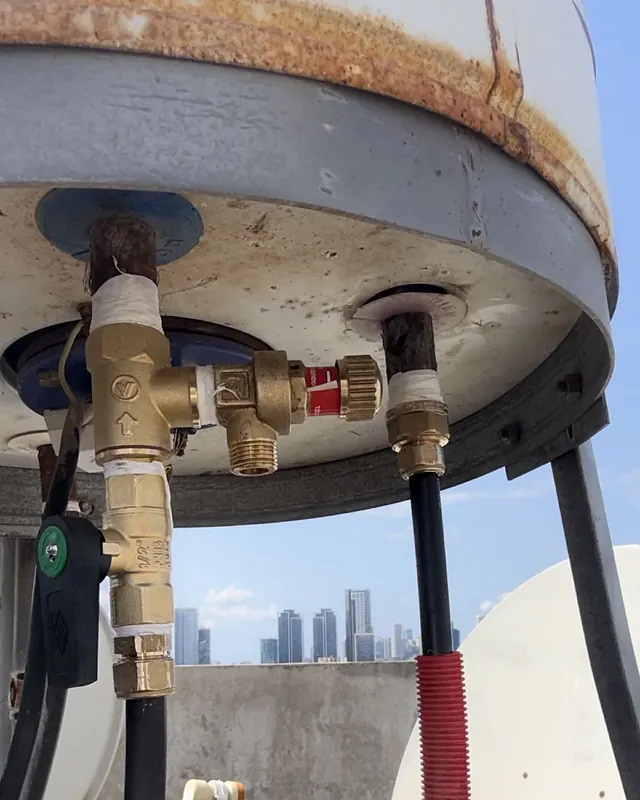תחתית דוד מים על גג, עם ברזים ומחברי פליז וצינורות שמחוברים אליו